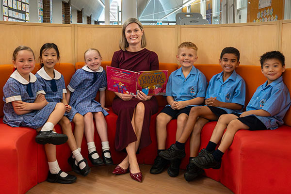 Principal with group of students reading a book inside library